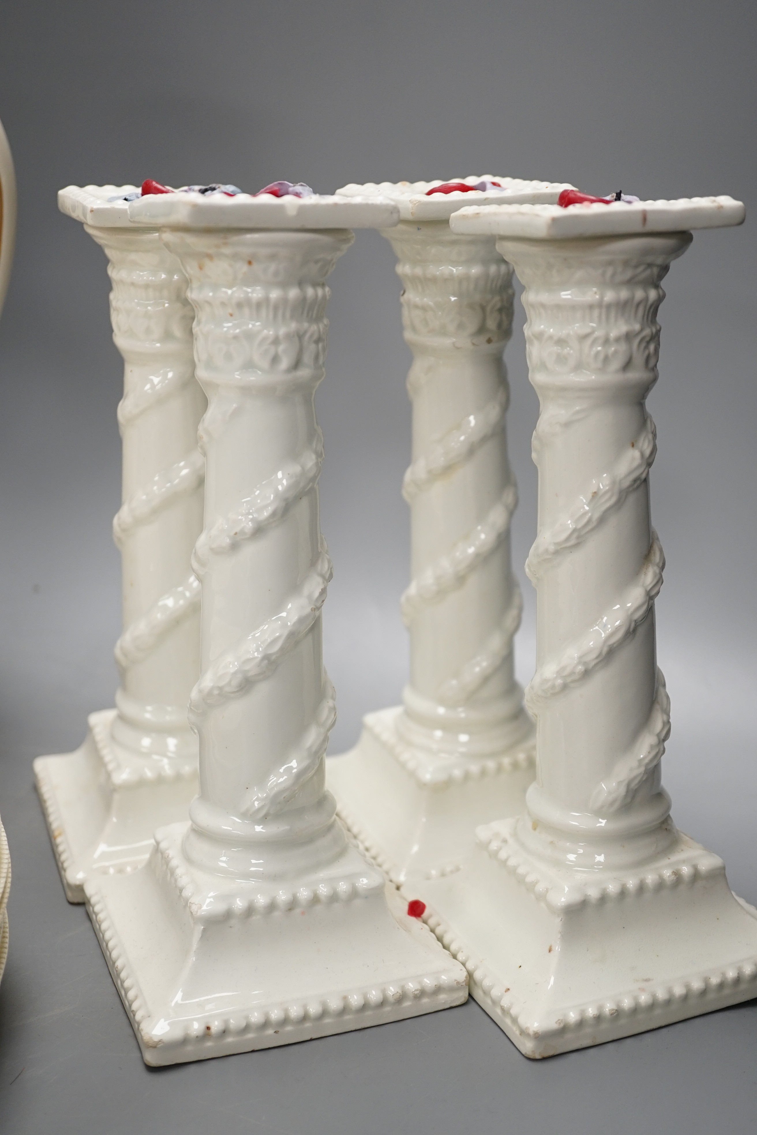 A set of seven early 19th century creamware plates, four later creamware candlesticks and an ivory ground jug. Tallest piece 33cm